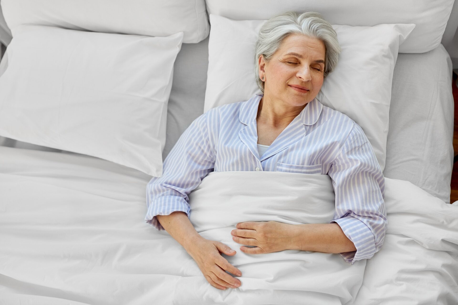 happy senior woman sleeping in bed at home bedroom