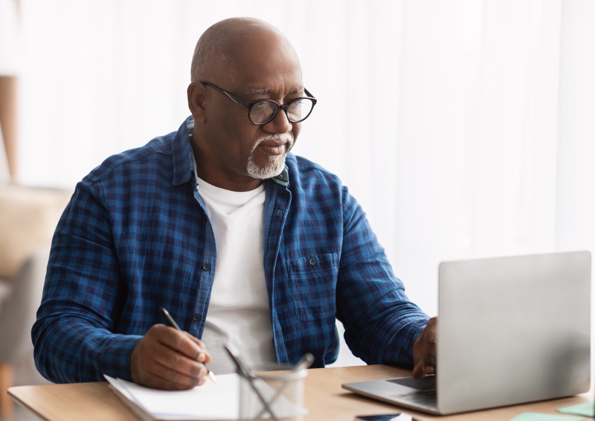 Man Using Laptop And Writing Report Taking Notes Working Online Sitting